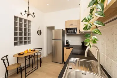 a kitchen with a table and a stainless steel refrigerator at Balda'Quand Médiéval in Carcassonne
