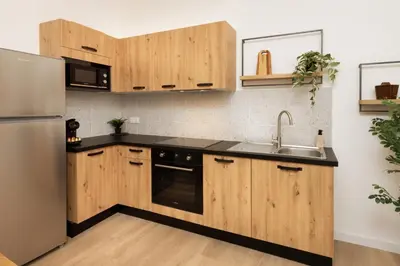 a kitchen with wooden cabinets and a stainless steel refrigerator at Balda'Quand Médiéval in Carcassonne