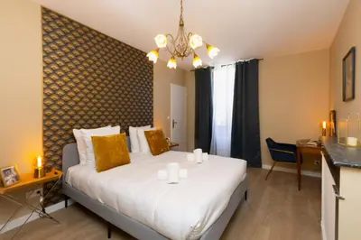 a bedroom with a large white bed in a room at Lueur des Années Dorées in Carcassonne