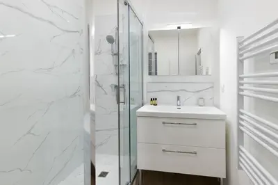 a white bathroom with a sink and a shower at Lueur des Années Dorées in Carcassonne