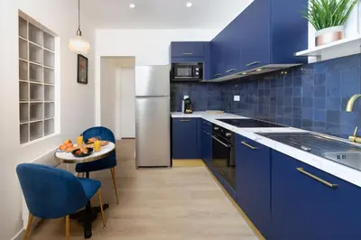 a blue kitchen with a small table and blue cabinets at Lueur des Années Dorées in Carcassonne