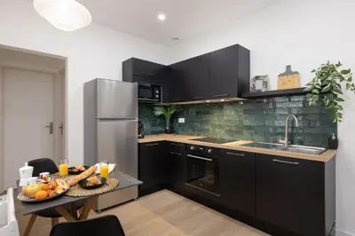 a kitchen with black cabinets and a table with fruit on it at MarQue Néo Art in Carcassonne