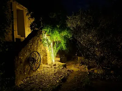 a stone wall with a light at night at Moulin de l’Arcas in Prémian