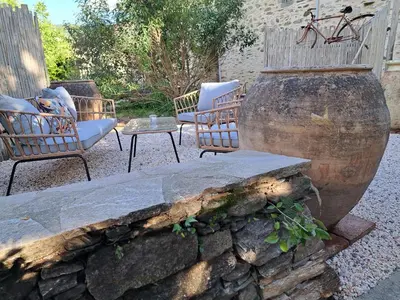 a patio with two chairs and a stone wall at Moulin de l’Arcas in Prémian