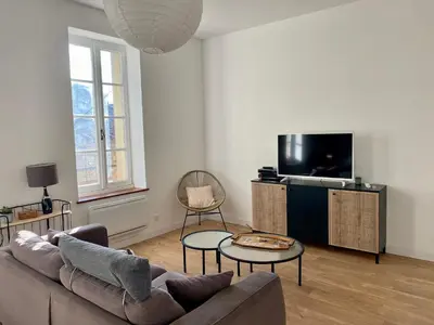 a bedroom with a bed and a chair and windows at Charmant T2 de 48m2 à 300m du centre ville in Lézignan-Corbières