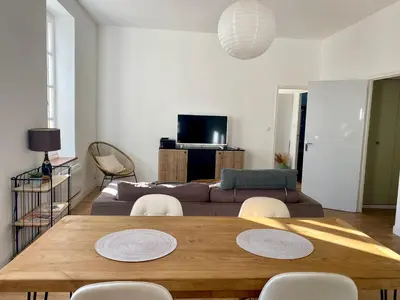 a living room with a couch and a kitchen at Charmant T2 de 48m2 à 300m du centre ville in Lézignan-Corbières