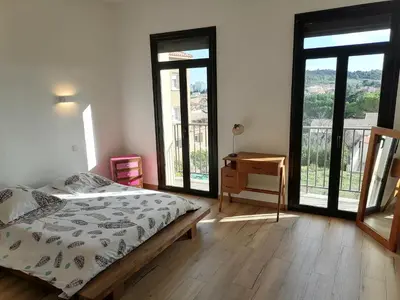 a bedroom with a bed and a desk and windows at Maison spacieuse, chaleureuse, Wifi et parking privé in Cases-de-Pène