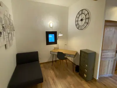 a room with a desk and a clock on the wall at Maison spacieuse, chaleureuse, Wifi et parking privé in Cases-de-Pène
