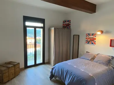 a bedroom with a bed and a sliding glass door at Maison spacieuse, chaleureuse, Wifi et parking privé in Cases-de-Pène
