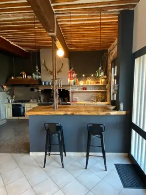 a kitchen with two bar stools at a counter at Maison spacieuse, chaleureuse, Wifi et parking privé in Cases-de-Pène