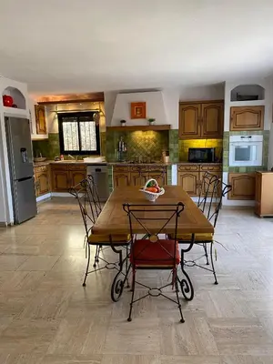 a large kitchen with a wooden table and chairs at Appartement spacieux, climatisé, parking privé, wifi et vue imprenable in Cases-de-Pène