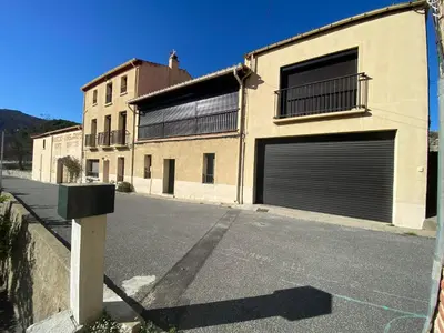a building with two garage doors on a street at Appartement spacieux, climatisé, parking privé, wifi et vue imprenable in Cases-de-Pène