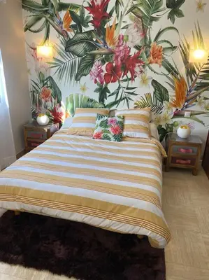 a bedroom with a large bed with a floral wallpaper at Appartement spacieux, climatisé, parking privé, wifi et vue imprenable in Cases-de-Pène