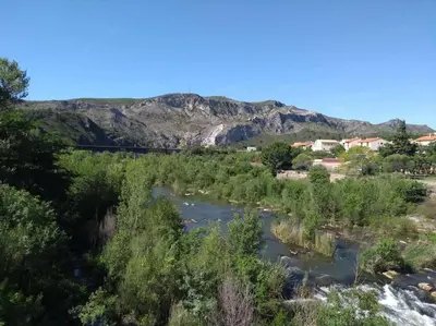 a river with trees and mountains in the background at Appartement neuf tout confort, climatisé, parking privé et wifi in Cases-de-Pène