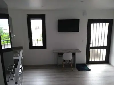 a room with a table and a chair and two windows at Appartement neuf tout confort, climatisé, parking privé et wifi in Cases-de-Pène