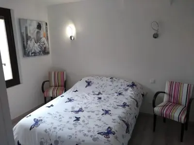 a bedroom with a bed and two chairs at Appartement neuf tout confort, climatisé, parking privé et wifi in Cases-de-Pène