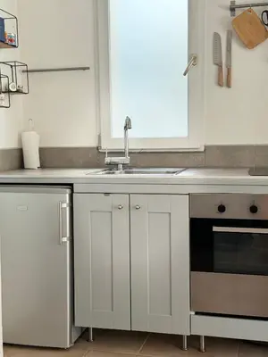 a kitchen with white cabinets and a sink and a window at La vue de la calade in Peyriac-de-Mer