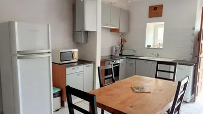 a kitchen with a wooden table and a refrigerator at Domaine Castel Negre Alet Les Bains in Alet-les-Bains