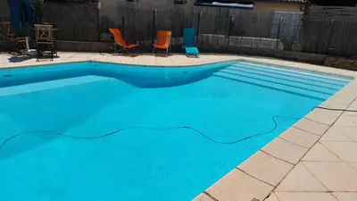a blue swimming pool with two chairs and a table at Domaine Castel Negre Alet Les Bains in Alet-les-Bains