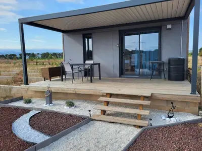 a house with a wooden deck with a table at Chalet confortable 2 chambres près du lac de Jouarres - FR-1-783-8 in Olonzac