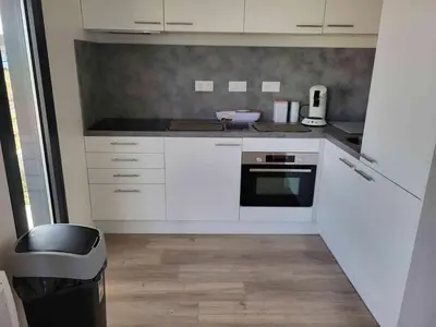 a kitchen with white cabinets and a black oven at Chalet confortable 2 chambres près du lac de Jouarres - FR-1-783-8 in Olonzac