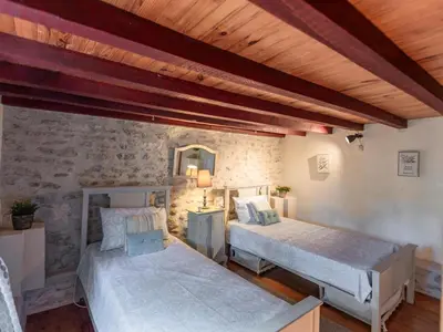 a bedroom with two beds and a stone wall at Le Pigeonnier de Villefloure in Montréal