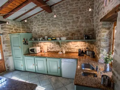 a kitchen with green cabinets and a stone wall at Le Pigeonnier de Villefloure in Montréal