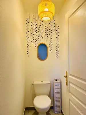 a bathroom with a toilet and a chandelier at Appartement Chez Rose in Narbonne