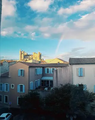 a rainbow in the sky over some buildings at Appartement Chez Rose in Narbonne