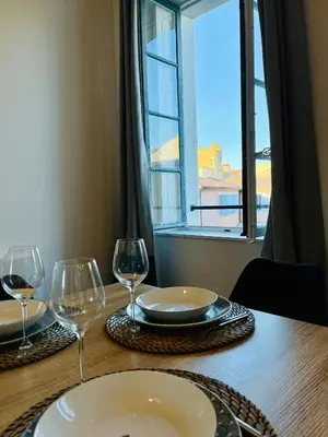 a table with two glasses and a plate and a window at Appartement Chez Rose in Narbonne