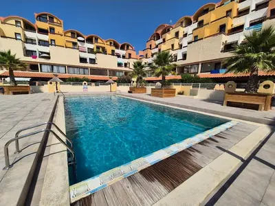 a swimming pool in front of a building at L'Escapade Gruissanaise, appartement 1 chambre, loggia, climatisation, wifi avec piscines de mi-mai à mi-septembre dans résidence in Gruissan