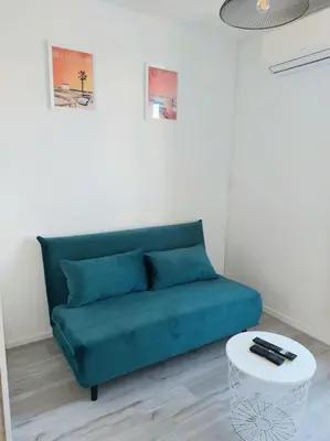 a blue couch in a living room with a table at L'Escapade Gruissanaise, appartement 1 chambre, loggia, climatisation, wifi avec piscines de mi-mai à mi-septembre dans résidence in Gruissan
