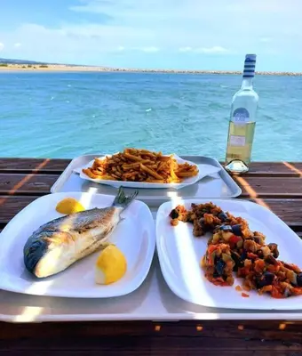 a tray with two plates of food on a table by the ocean at L'Escapade Gruissanaise, appartement 1 chambre, loggia, climatisation, wifi avec piscines de mi-mai à mi-septembre dans résidence in Gruissan