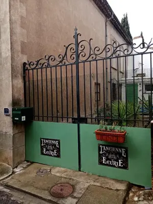 a green fence with signs on it next to a building at Cozy self contained modern home near Carcassonne in Badens