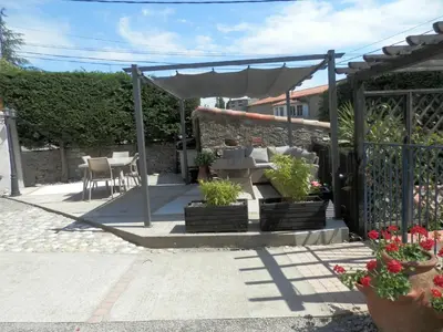 a patio with a pergola and a table and chairs at Maison de Laura in Salsigne