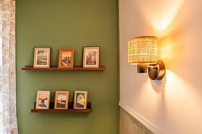 a room with a green wall with shelves and a lamp at Oasis Urbaine Narbonne in Narbonne