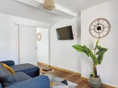 a living room with a blue couch and a plant at Le Iéna in Carcassonne