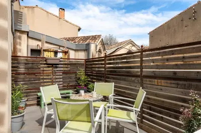 a patio with chairs and a table in front of a fence at Le Coste - Free parking - Central - Wifi -netflix in Carcassonne