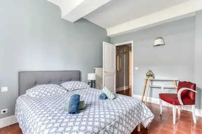 a bedroom with a bed and a red chair at Le Coste - Free parking - Central - Wifi -netflix in Carcassonne
