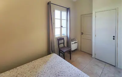 a bedroom with a bed and a chair next to a window at Pet Friendly Home In Saint-Laurent-De-La-Ca in Saint-Laurent-de-la-Cabrerisse