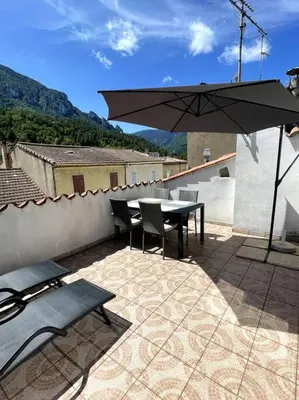 a table and chairs and an umbrella on a patio at Townhouse in Southern France with a wonderful view and close to a Swimming pool in Axat