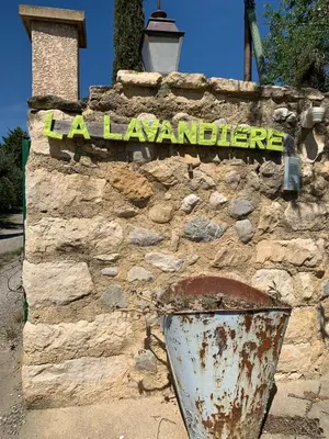 a sign on a stone wall with a bucket at LA LAVANDIERE Famille Amis Relais Motards in Peyriac-de-Mer