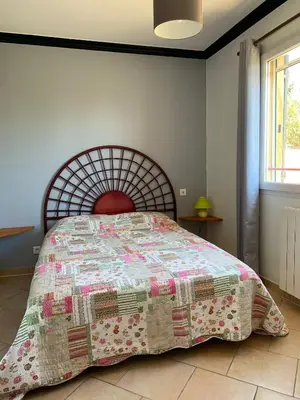 a bedroom with a bed with a quilt on it at Gite LA FONTAINE Famille Amis Relais Motards in Peyriac-de-Mer