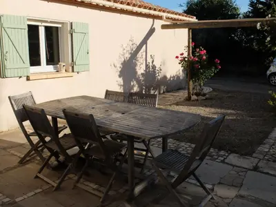 a wooden table and chairs in front of a house at Gite LA FONTAINE Famille Amis Relais Motards in Peyriac-de-Mer