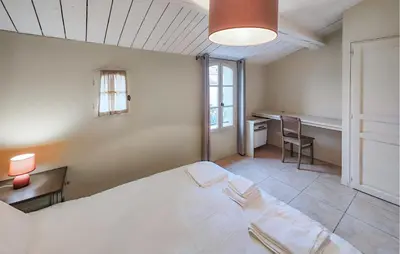 a bedroom with a large white bed and a desk at 2 Bedroom Stunning Home In Saint-Laurent-De-La-Ca in Saint-Laurent-de-la-Cabrerisse