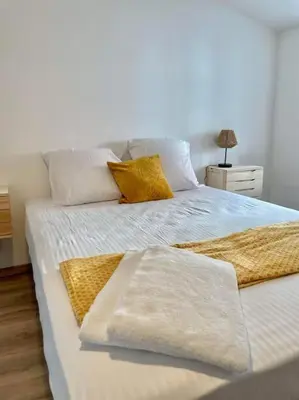 a white bed with two pillows on top of it at * Maison chez J&J - Cité médiévale * in Carcassonne