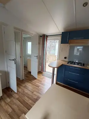 a kitchen with blue cabinets and a table in a room at MOBIL HOME LUCKY climatisé camping PORT LA NOUVELLE in Port-la-Nouvelle