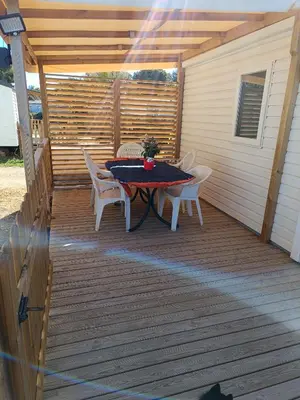 a patio with a table and chairs on a deck at MOBIL HOME LUCKY climatisé camping PORT LA NOUVELLE in Port-la-Nouvelle