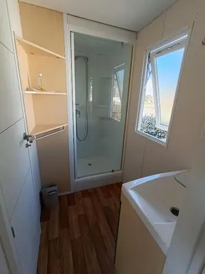 a bathroom with a shower and a sink and a window at MOBIL HOME LUCKY climatisé camping PORT LA NOUVELLE in Port-la-Nouvelle
