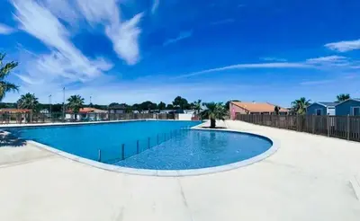 a large swimming pool with blue water in a yard at MOBIL HOME LUCKY climatisé camping PORT LA NOUVELLE in Port-la-Nouvelle